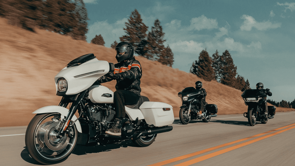 Group of riders led by a 2025 Harley-Davidson® Street Glide® in white on a scenic highway near Missouri City, TX, showcasing its modern touring silhouette in motion.