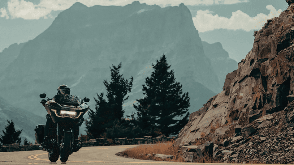 Rider leans into a mountain curve on the 2025 Harley-Davidson® Road Glide near Bellaire, TX, showing off its frame-mounted fairing and long-haul touring capability.