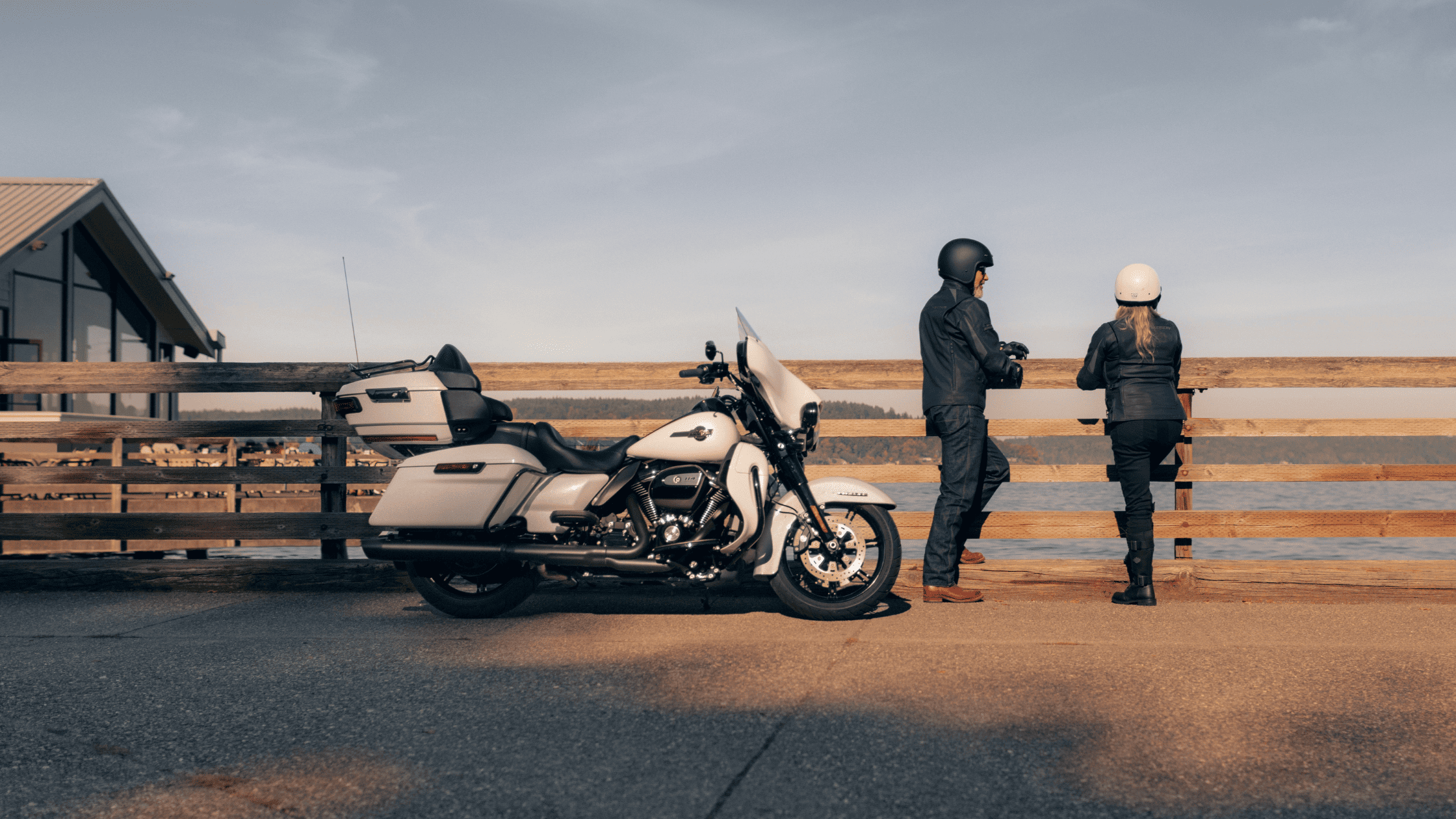 Two individuals beside a 2024 Harley-Davidson® Ultra Limited® motorcycle parked on a dock in Houston, TX.