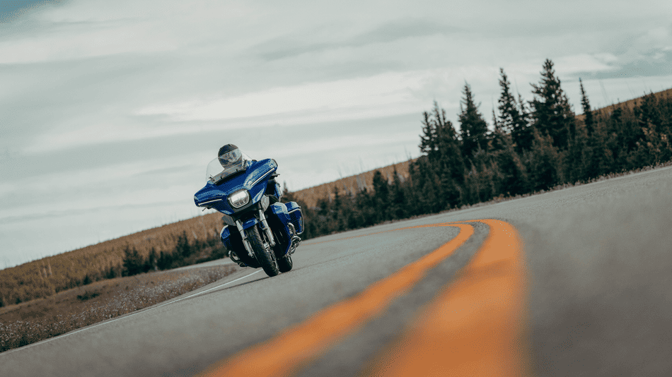2025 Harley-Davidson® Street Glide® Ultra in bright blue riding along a curvy open road near Missouri City, TX, highlighting infotainment and premium touring features.
