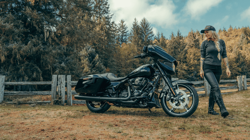 2025 Harley-Davidson® Street Glide in sleek black parked near a rustic fence and trees, featured in a lifestyle scene near Missouri City, TX.